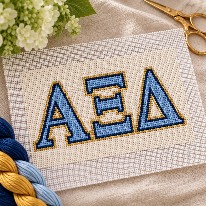Alpha Xi Delta needlepoint canvas featuring ΑΞΔ letters over light blue, dark blue, and gold stripes