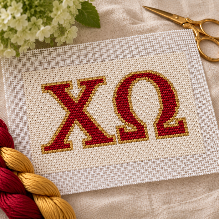 Chi Omega needlepoint canvas with ΧΩ letters and gold crescent moon motif over cardinal red and cream stripes